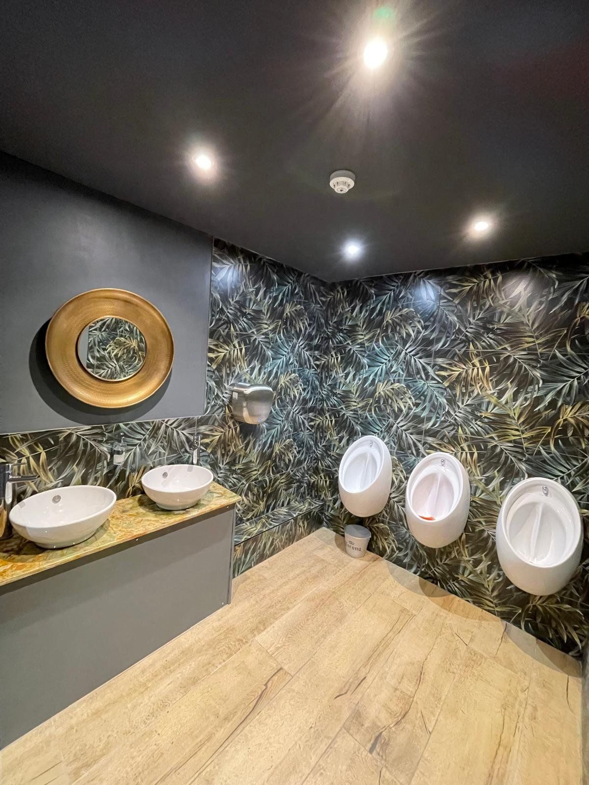 Gents' toilets with urinals and tropical wallpaper