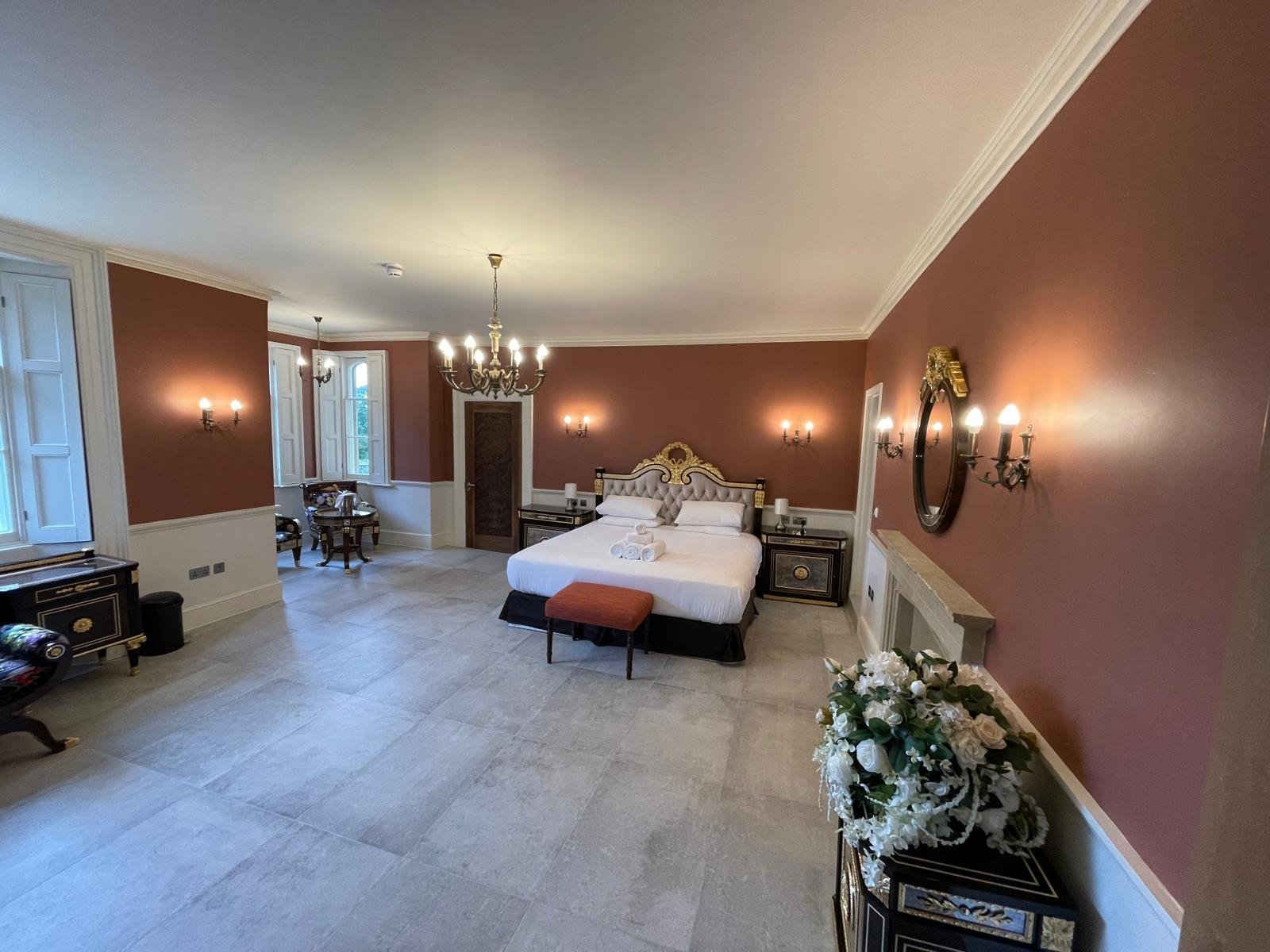 Period bedroom refurbishment with deep red walls and chandelier completed in Oxfordshire
